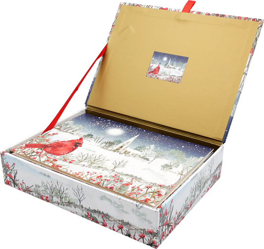 Card box with a cardinal perches on snow- and berry-laden branches, with a country church in the distance.