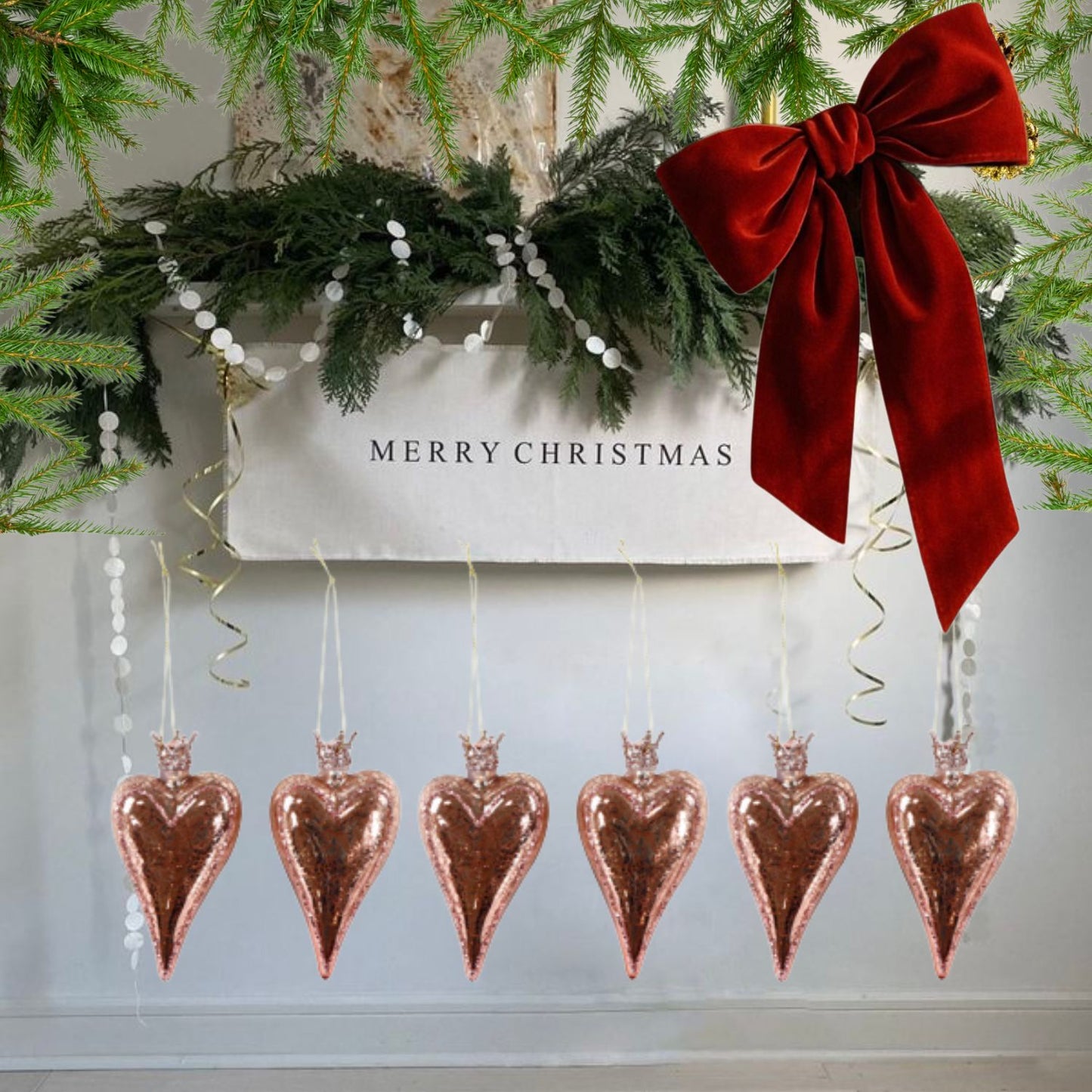 Rose gold heart-shaped glass ornaments hanging below a red bow on a Christmas-themed background.