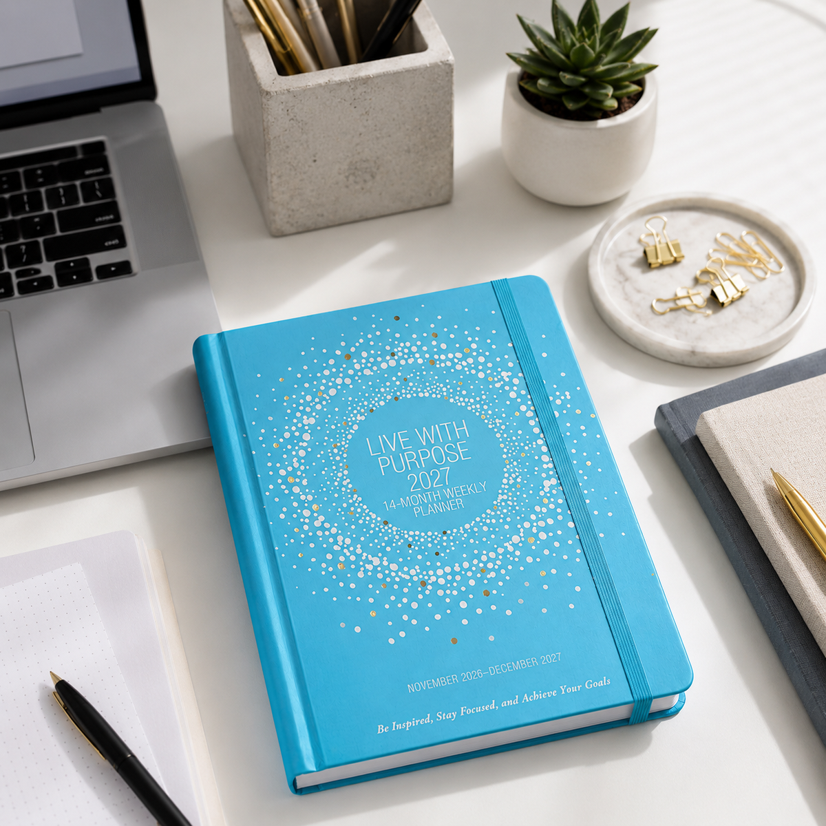 Blue planner titled 'Live with Purpose 2023' on a desk with a laptop and office supplies.