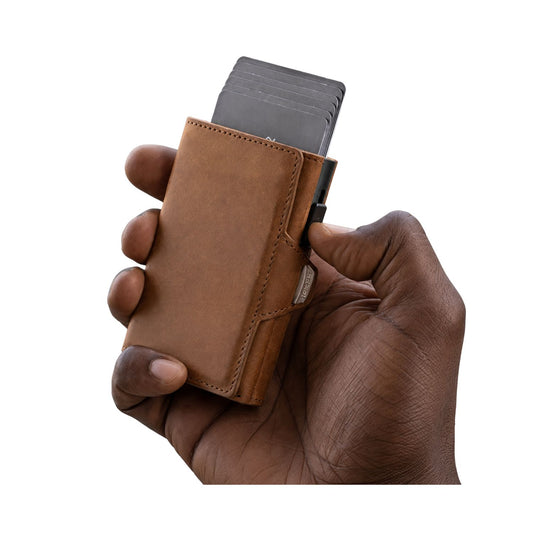Hand holding a brown leather wallet with a card holder on a white background