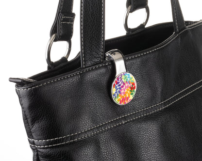 Black handbag with a colorful floral patterned tag on a white background