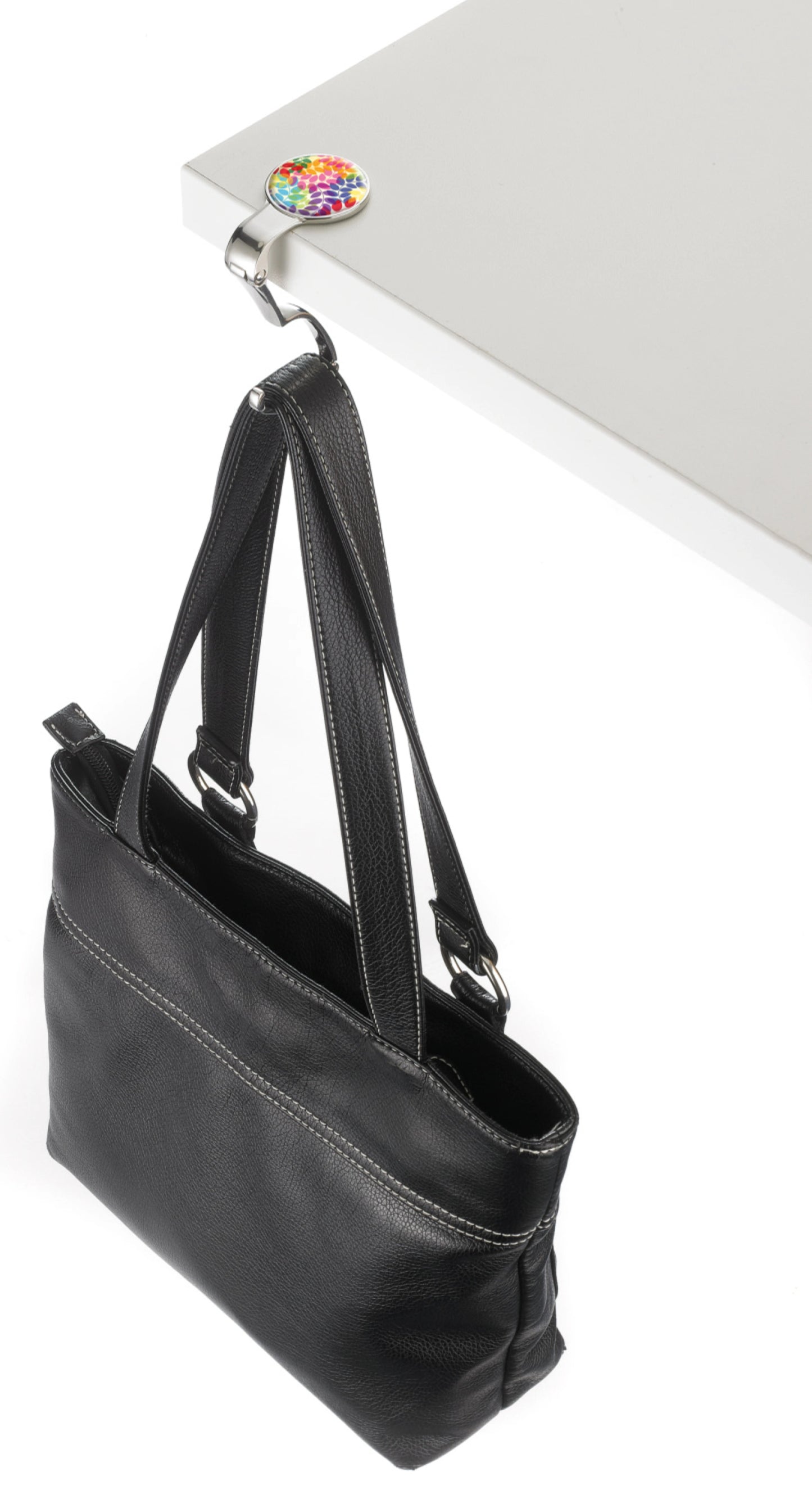 Black handbag on a white surface with a colorful flower bag holder
