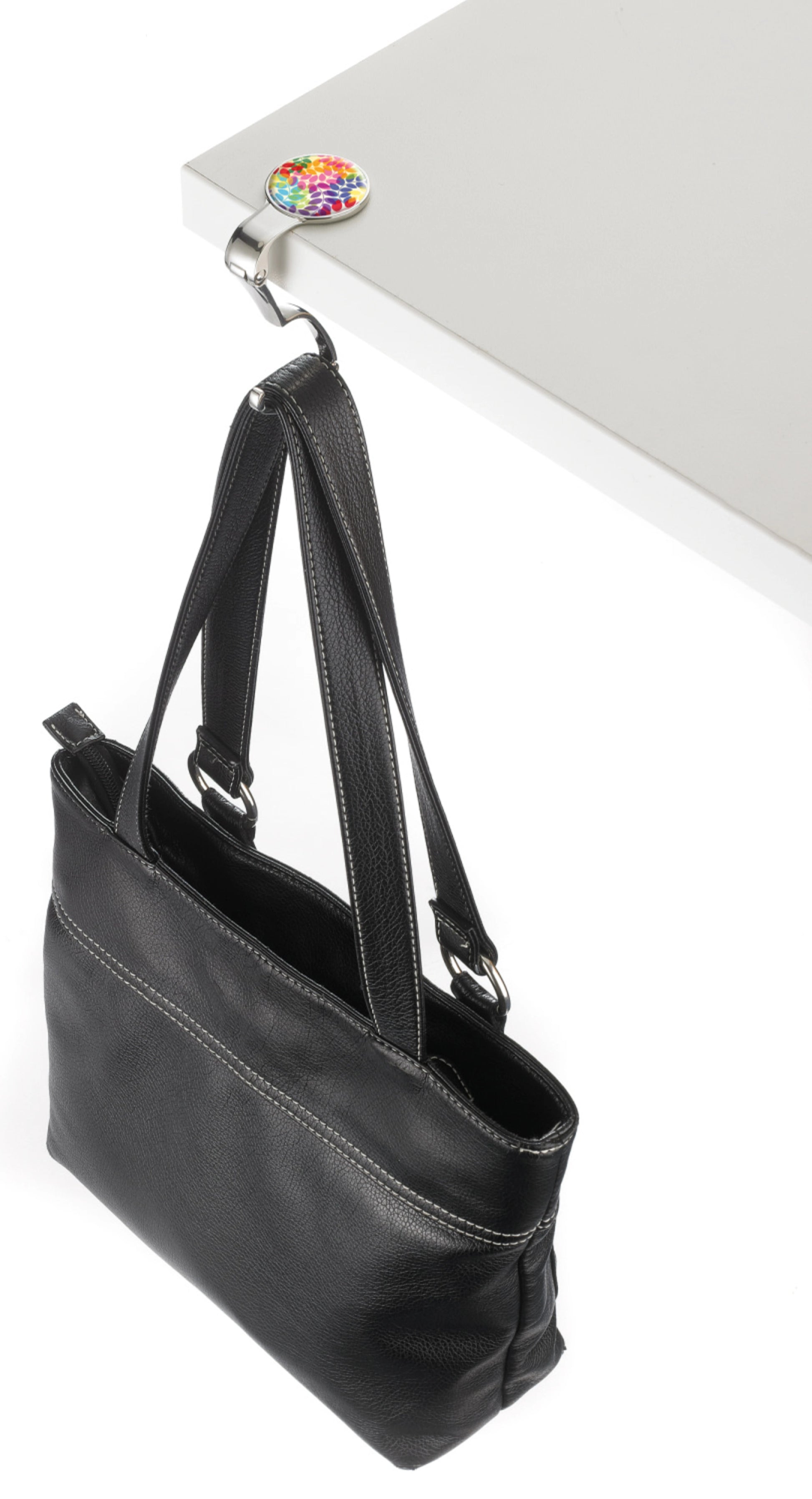 Black handbag on a white surface with a colorful flower bag holder