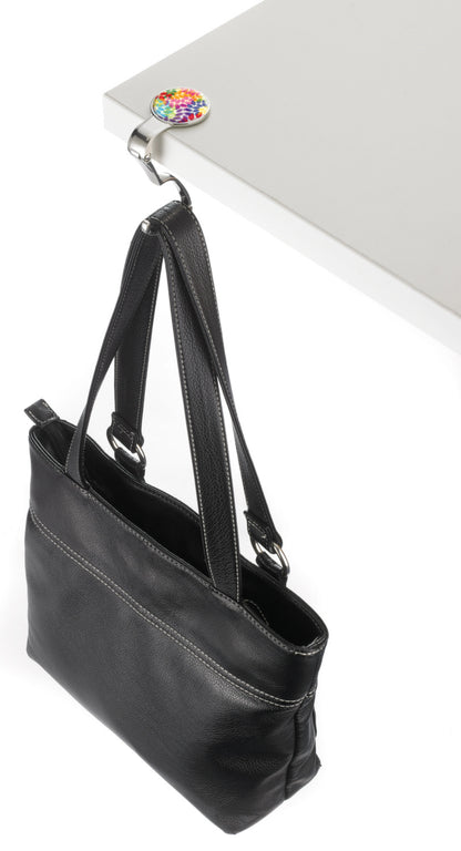 Black handbag on a white surface with a colorful flower bag holder