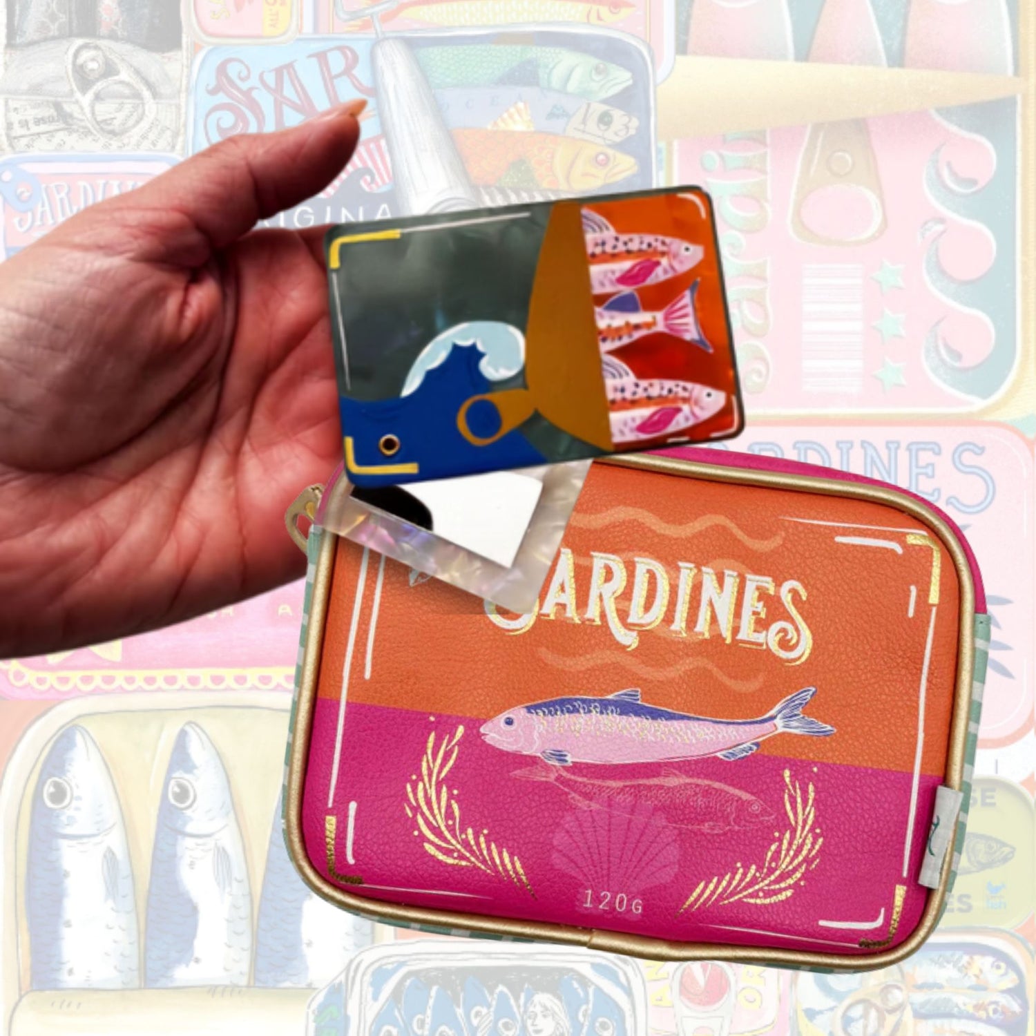 Colorful pouch and compact mirror  with fish design held by a hand against a patterned background