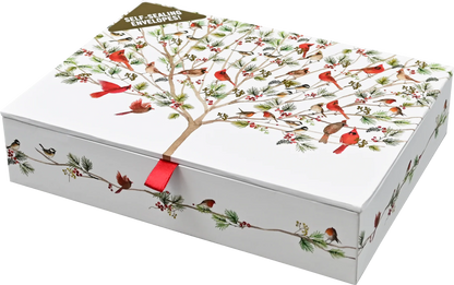 A white rectangular gift box with a lid printed with a winter tree of life design featuring red cardinals, green pine branches, and small birds. A red ribbon tie is visible at the center front, and a small tag at the top reads 'SELF-ADHESIVE ENVELOPE!'.