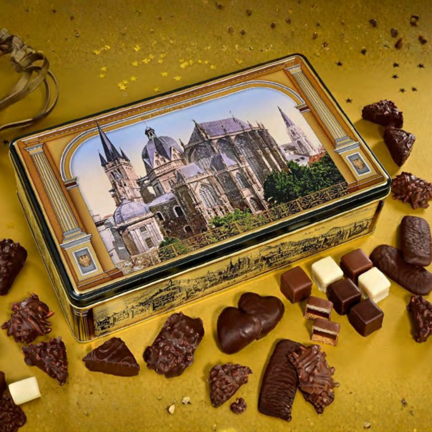 Decorative chocolate tin with a cityscape design surrounded by assorted chocolates on a yellow background