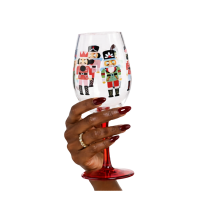 Acrylic wine glass with nutcracker design held by a hand on a white background