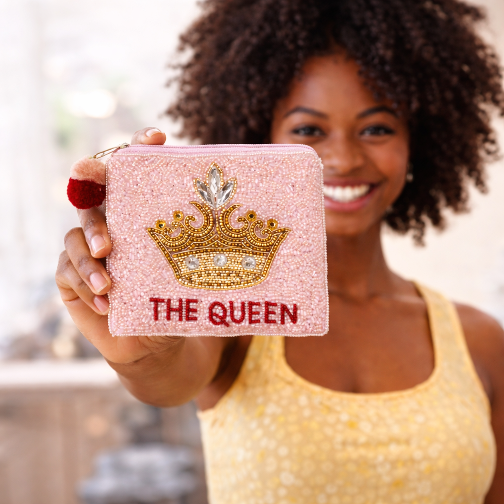 Woman holding a pink glittery pouch with a crown and 'The Queen' text.