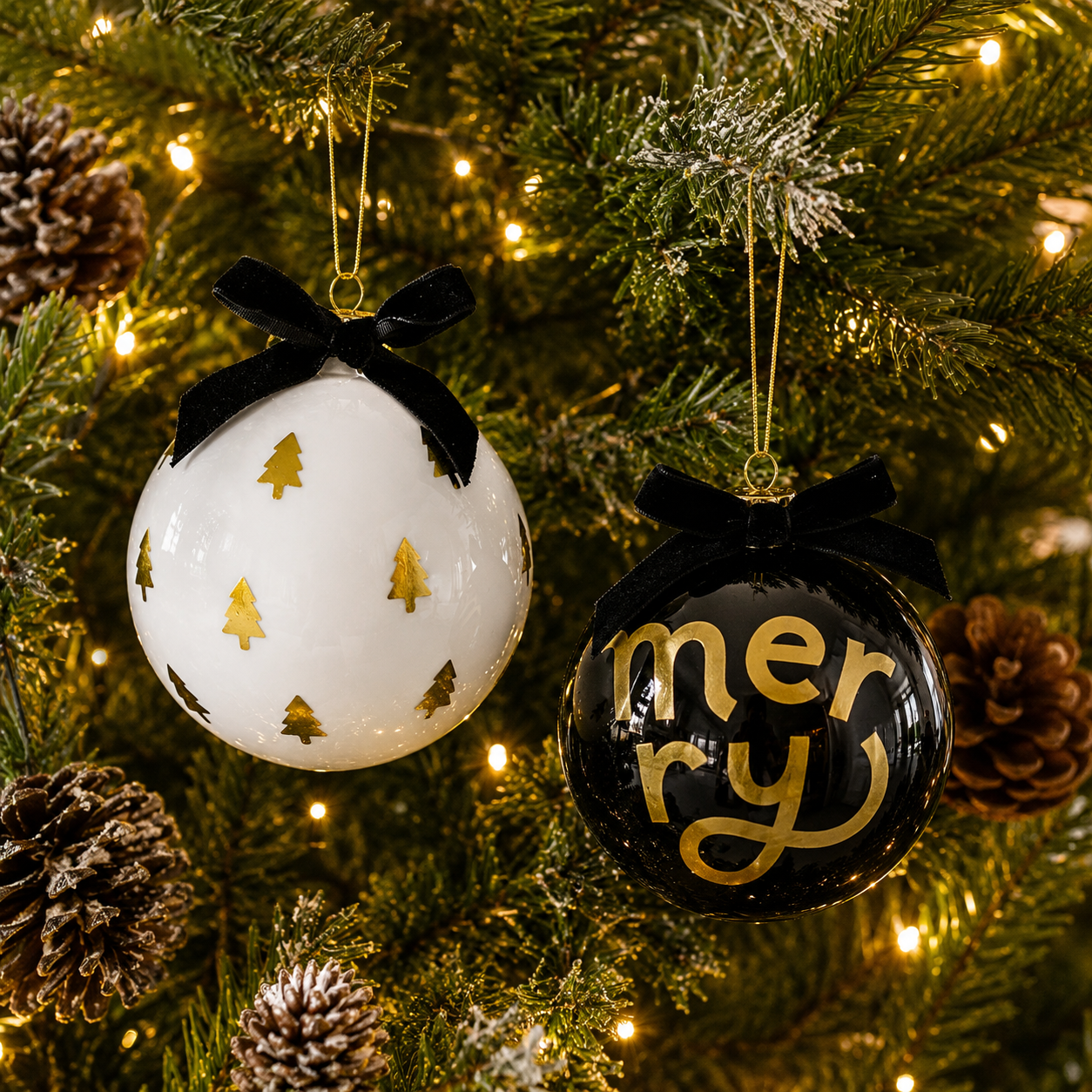 Boxed set of two glass Christmas ornaments with festive gold tree design and written Merry, velvet bows, and elegant holiday gift packaging