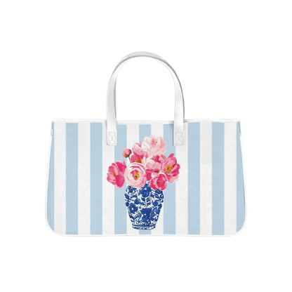 This spacious canvas tote features soft blue-and-white stripes paired with a vibrant floral arrangement in a classic blue porcelain vase.