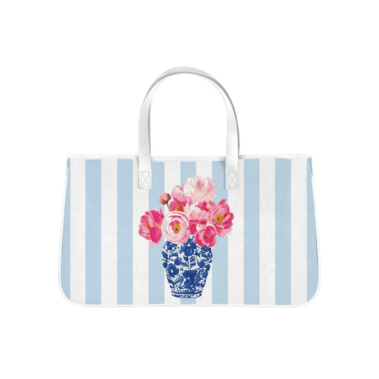 This spacious canvas tote features soft blue-and-white stripes paired with a vibrant floral arrangement in a classic blue porcelain vase.