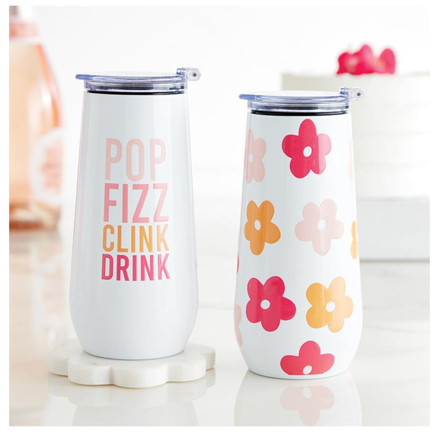 Two tumblers; one with 'Pop Fizz Clink Drink' text and the other with floral design on a white background.