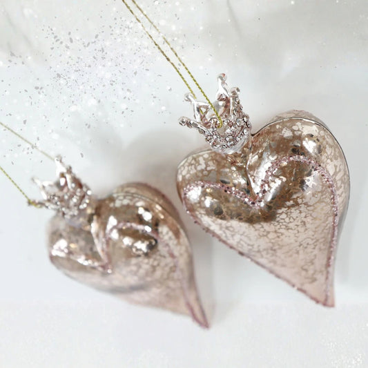 Two heart-shaped Christmas glass ornaments with crowns on a white background