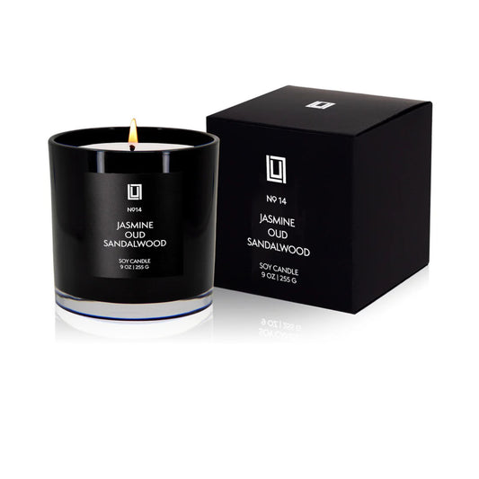 Black candle with Jasmine Oud Sandalwood scent next to its packaging on a white background