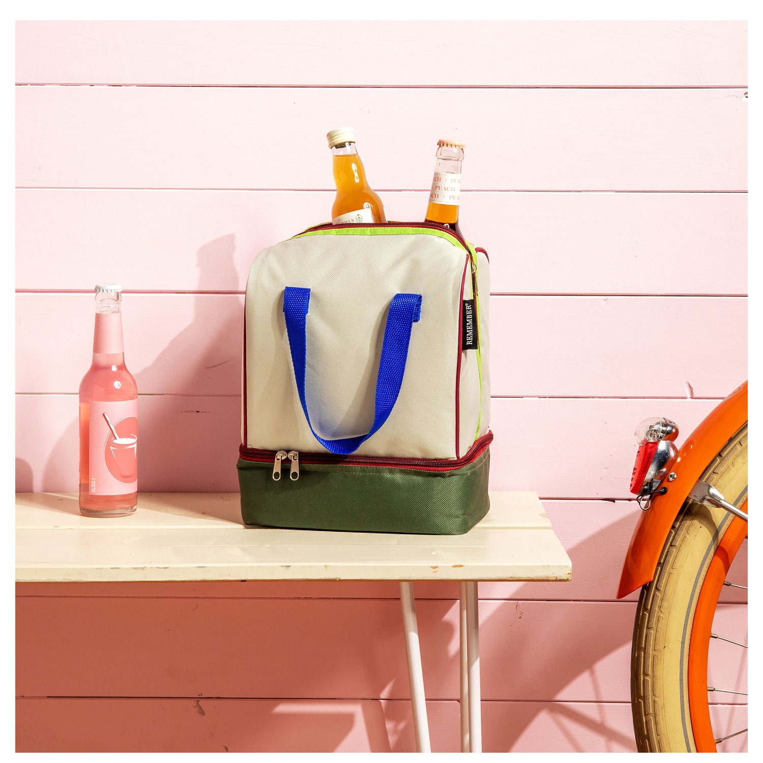 Colorful cooler bag with bottles on a pink wooden background