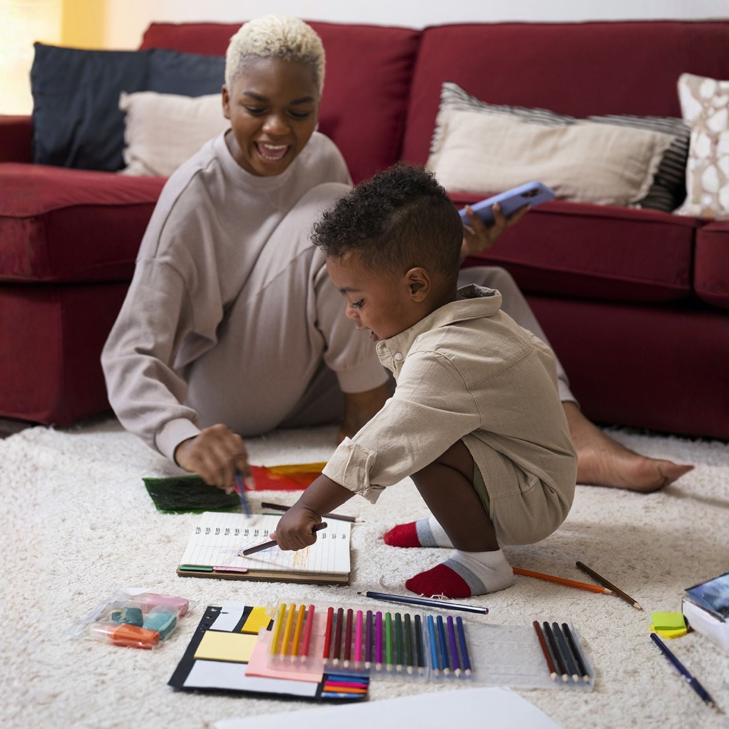 Woman and child sitting on the floor with art supplies in a living room.