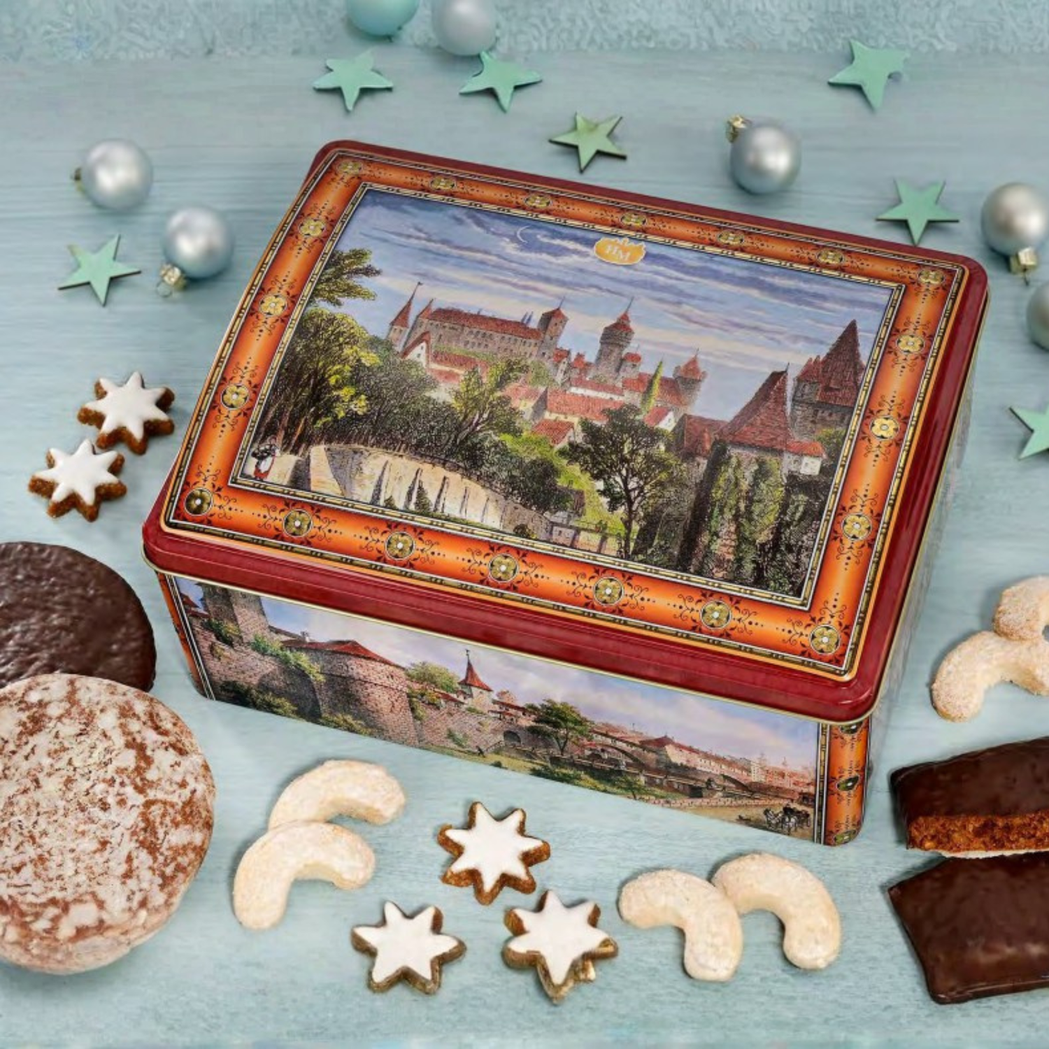 Decorative cookie tin with castle illustration surrounded by cookies on a blue surface.