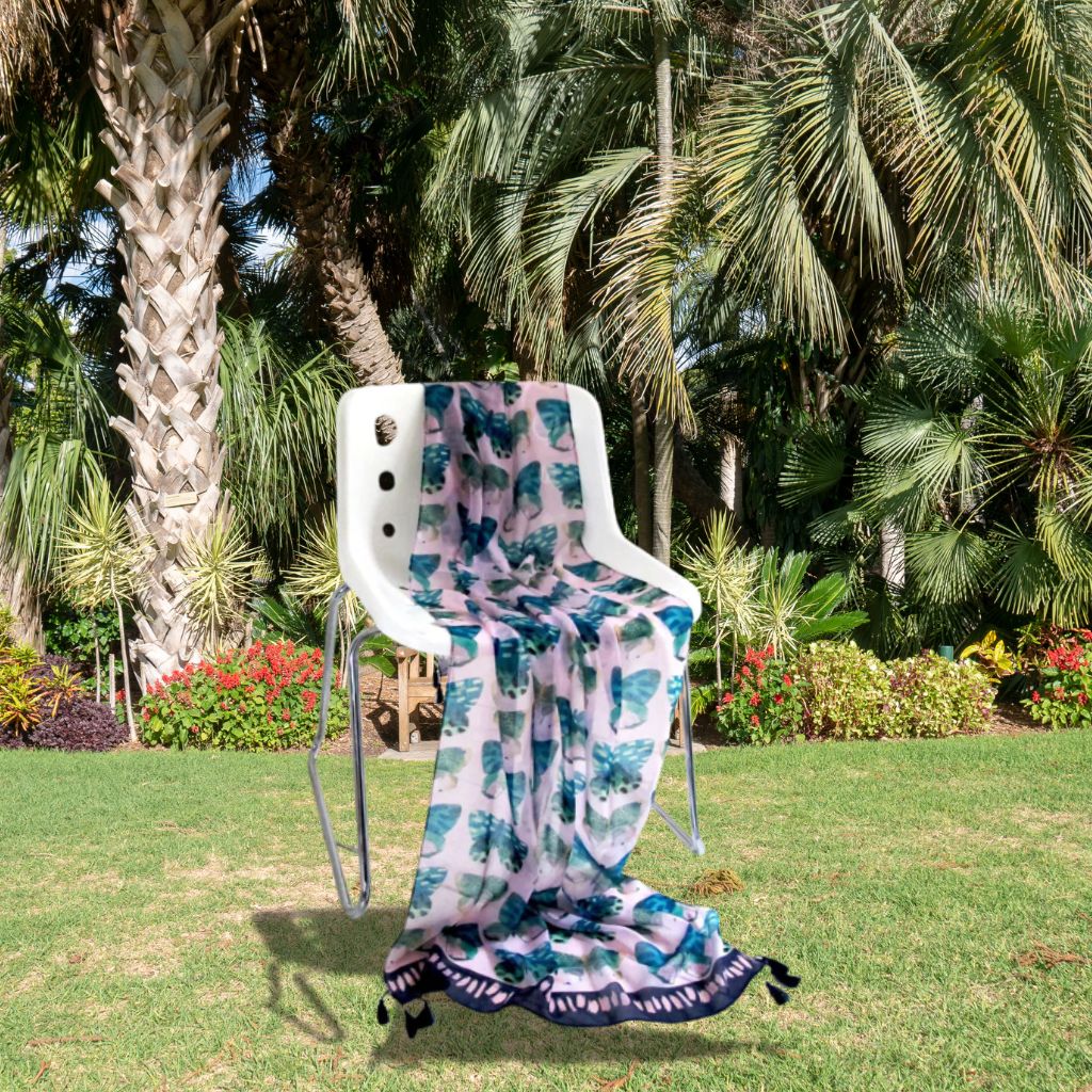 Chair with a colorful butterfly-patterned blanket draped over it, set against a tropical garden backdrop.
