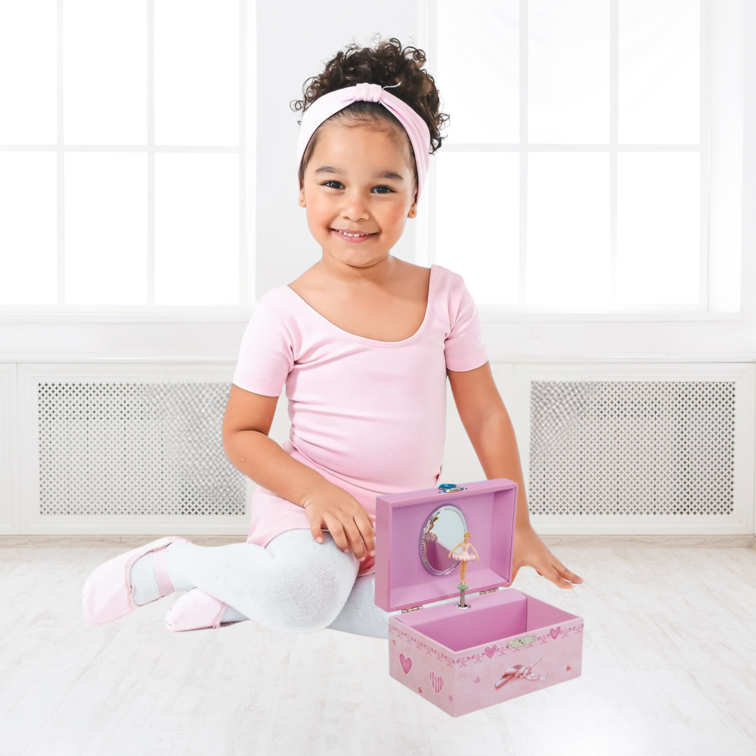 Young girl in a pink ballet outfit with a pink jewelry music box.