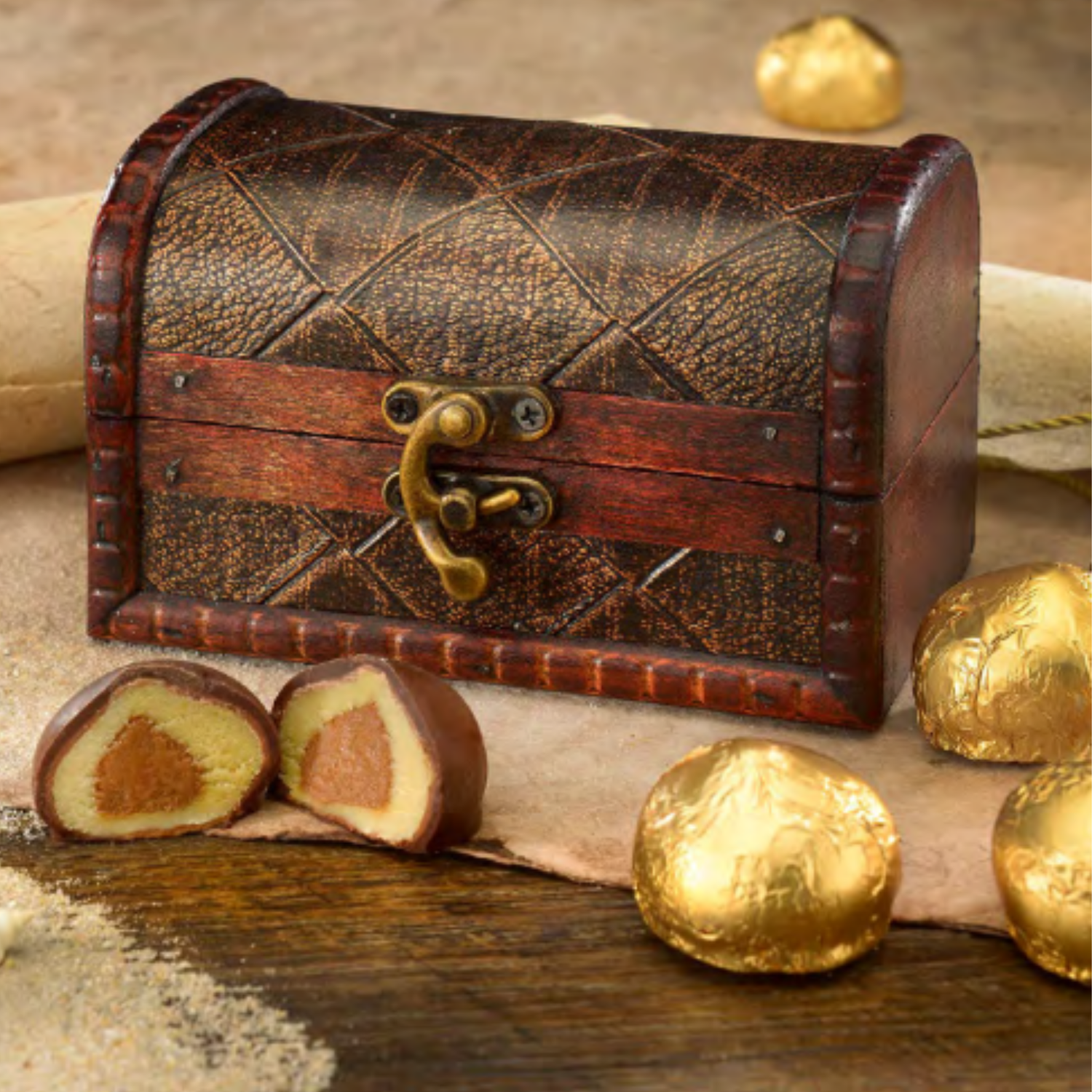 Wooden treasure chest with gold wrapped chocolates on a rustic background