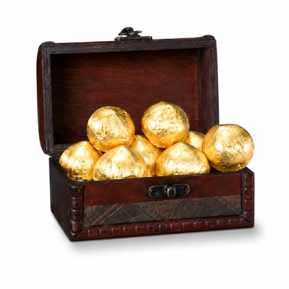 Wooden treasure chest filled with gold-colored chocolate Mozart kugeln on a white background