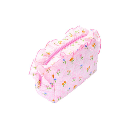 A pink quilted cosmetic pouch with a floral print and ruffled trim, shown on a plain white background.