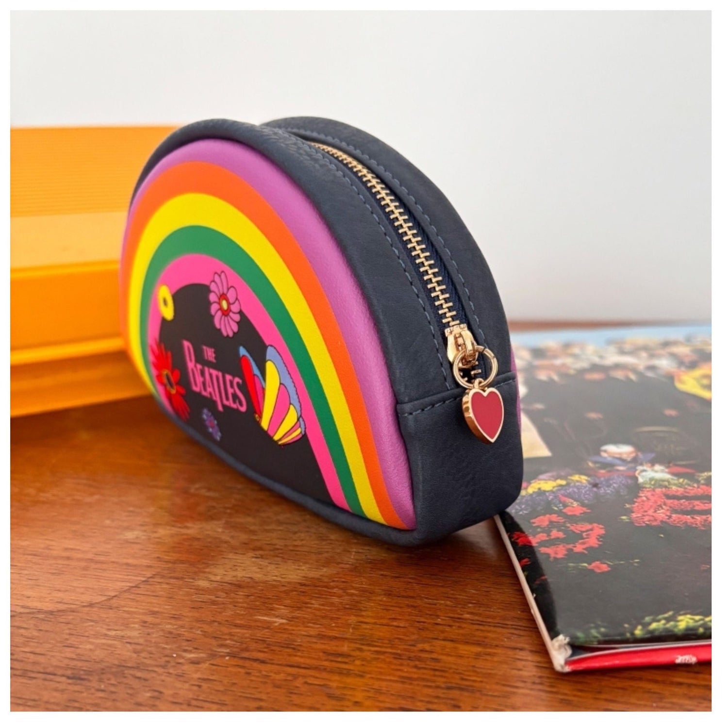Small pouch with rainbow design and 'The Beatles' logo on a wooden surface.
