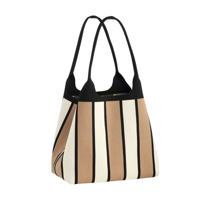 A structured tote bag with vertical stripes in beige, cream, and black, featuring black shoulder straps and a black top trim, shown against a plain white background.