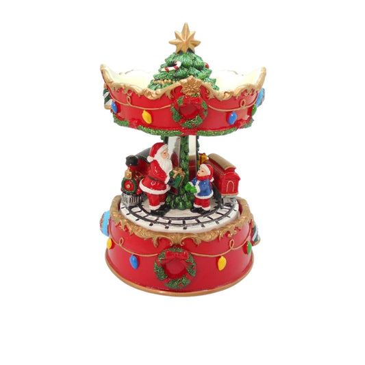 A festive Christmas carousel music box featuring Santa Claus, a decorated Christmas tree, snow, and colorful lights on a plain white background.