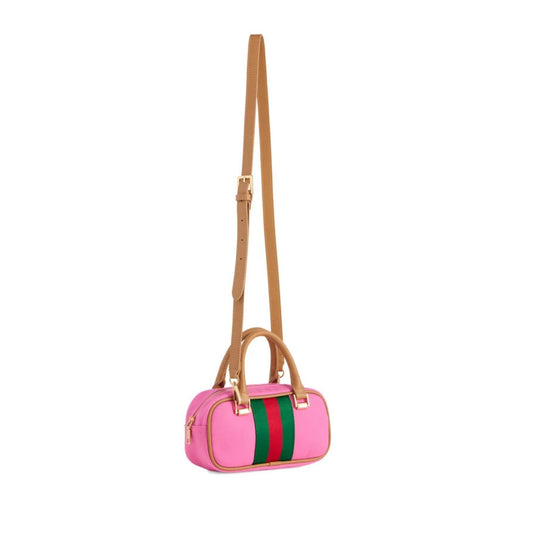 A pink cylindrical shoulder bag with a green and red web stripe on the front, tan leather handles and strap, and gold-tone hardware, shown on a plain white background.