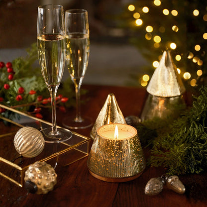 Two glasses of champagne with a lit candle and festive decorations on a wooden table.