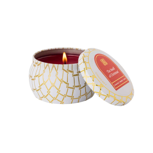 Candle in a decorative tin with a lit wick on a white background