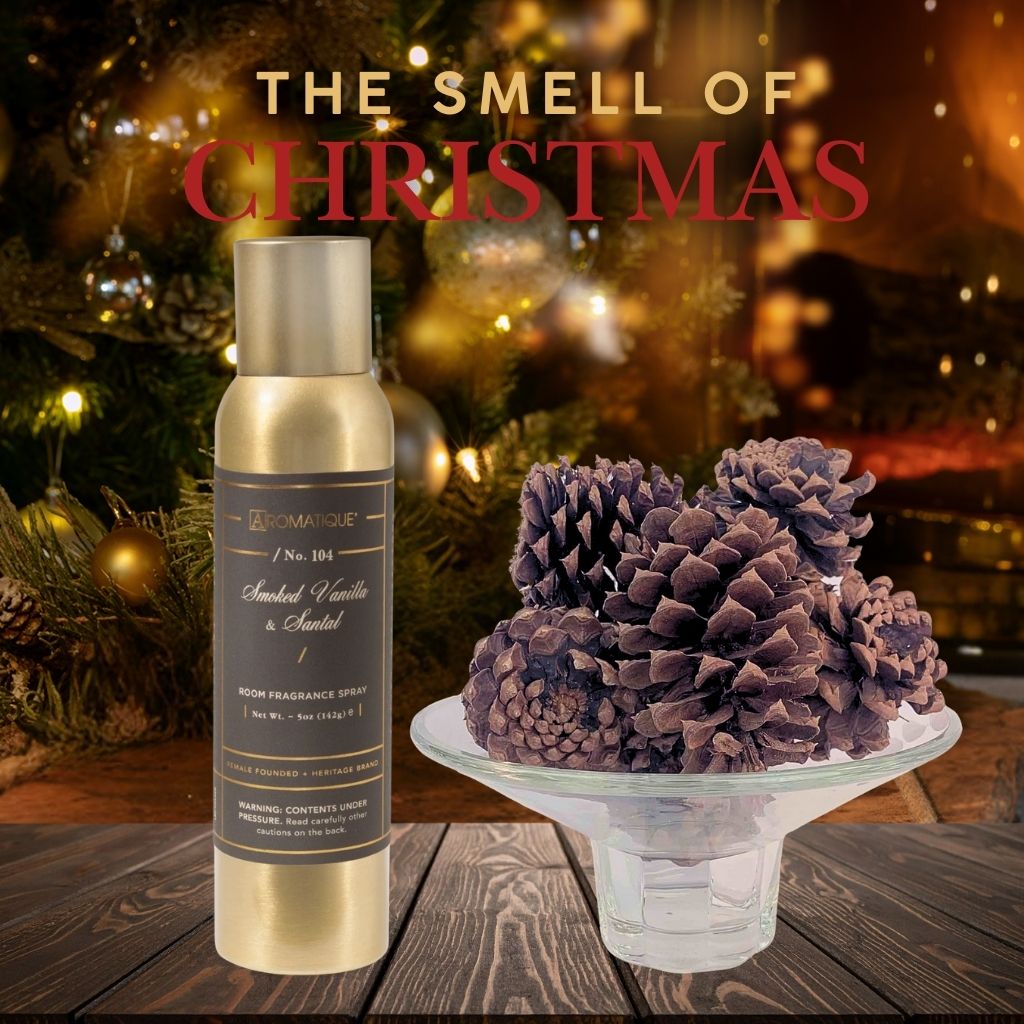 Room fragrance spray Smoked Vanille and Santal with decorative pinecones on a wooden surface with Christmas decorations in the background.