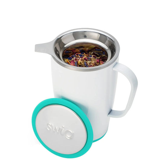 White mug with teal lid and silver infuser filled with tea leaves on a white background