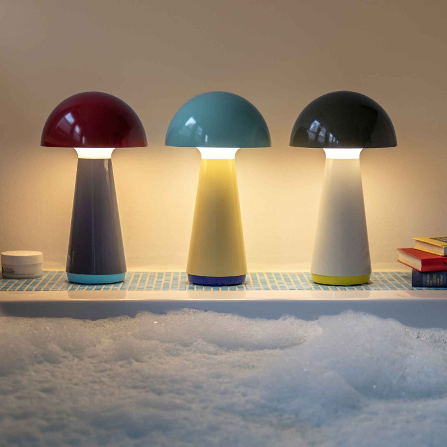 Three colorful mushroom-shaped lamps on a tiled surface with a soft, blurred background.
