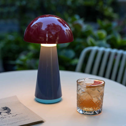 Mushroom-shaped lamp on a table with a glass of juice and a book