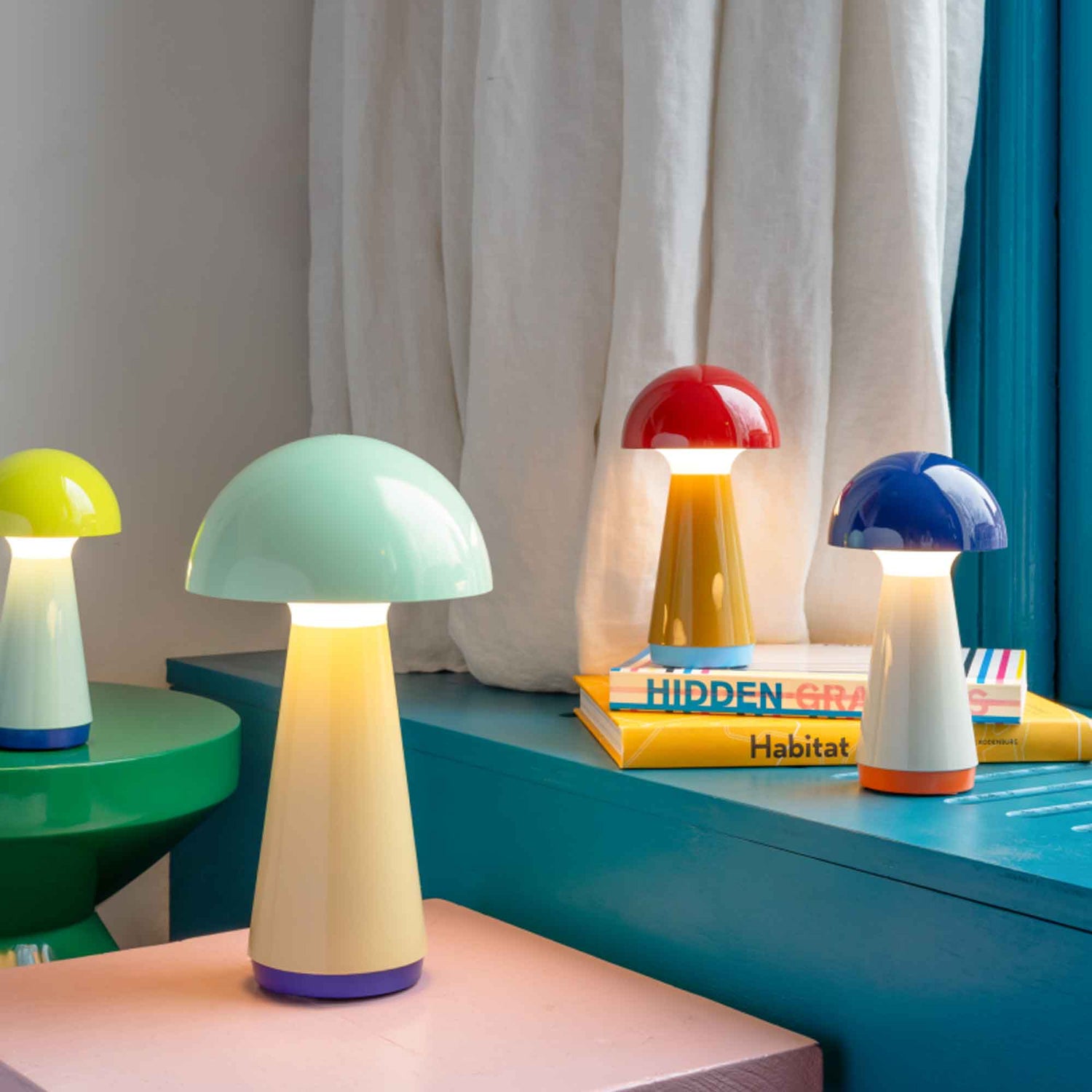 Colorful mushroom-shaped lamps on a shelf with a curtain in the background