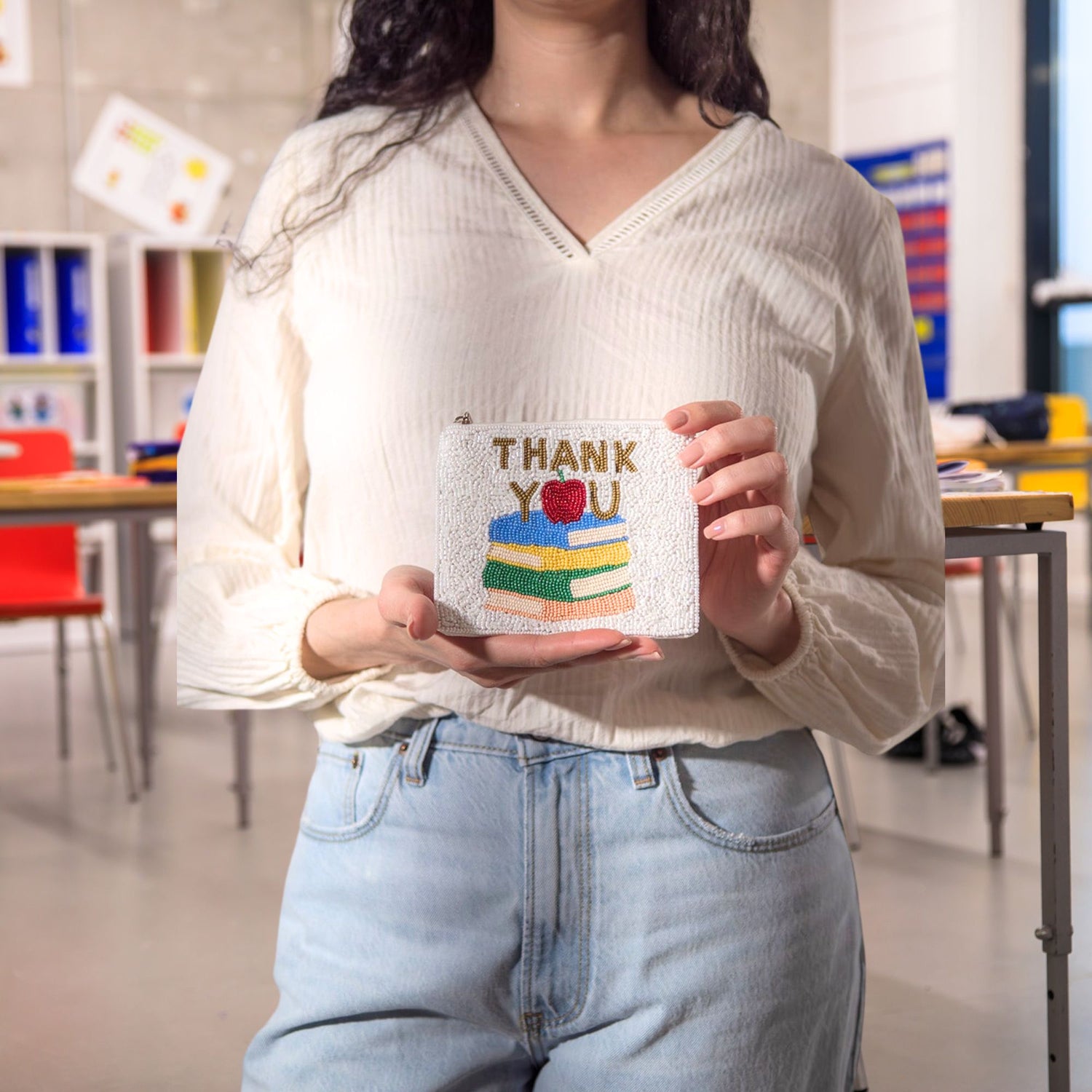 A young lady is holing the hand-beaded Thank You Teacher coin purse with books and apple.