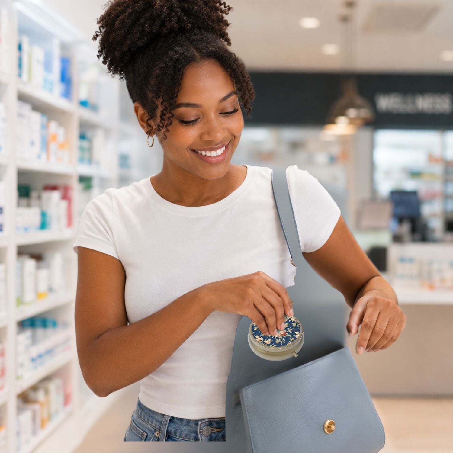 Young woman placing round dark blue floral pillbox into handbag in pharmacy setting